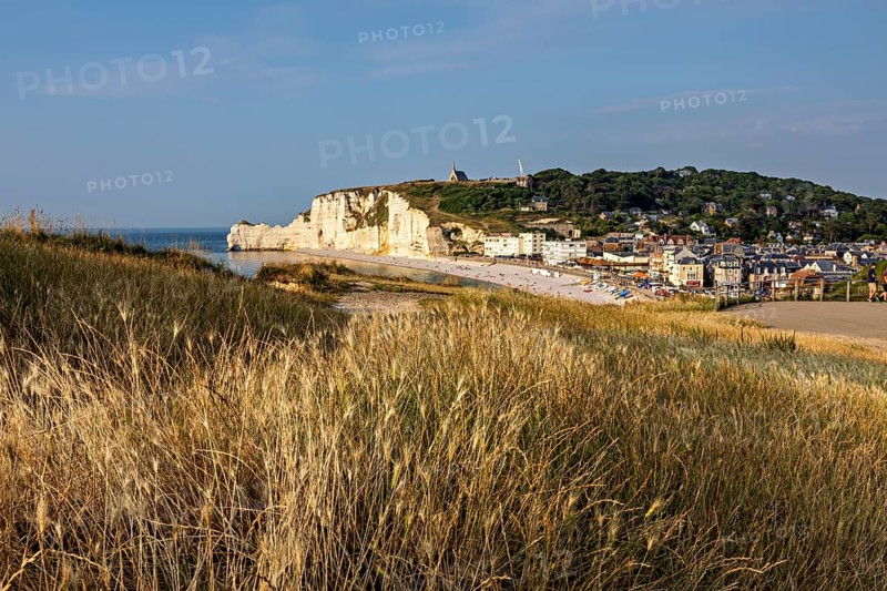 View of a seaside village with grassy cliffs overlooked by rocks, The cliffs and alabaster coast of Etretat in Normandy France