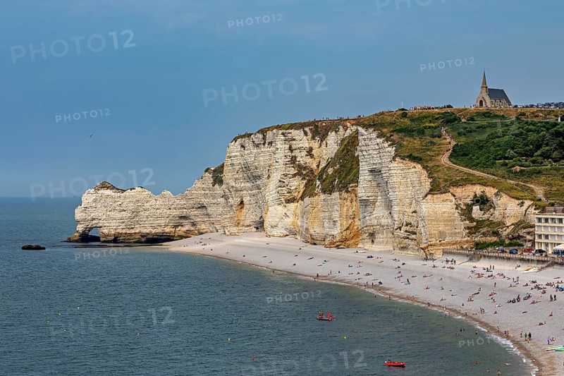 Beach with rocks and a small church on the hill, surrounded by a quiet village, The cliffs and alabaster coast of Etretat in Normandy France