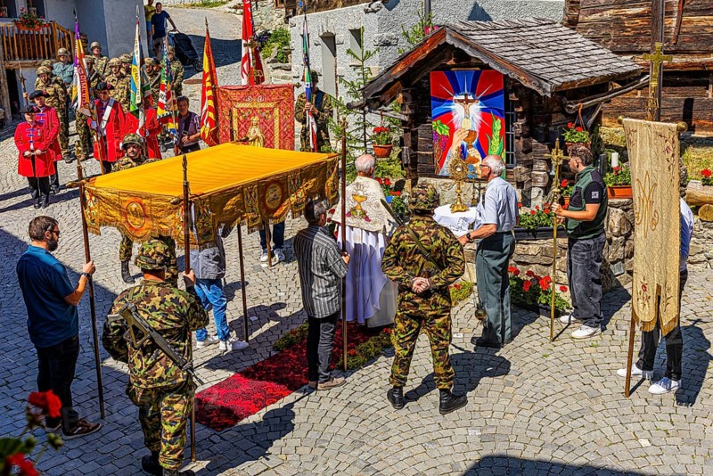 The priest celebrates a service at the flower-decorated altar during the Corpus Christi procession, historic town centre, Grimentz, Val d'Anniviers, Valais Alps, Canton Valais, Switzerland