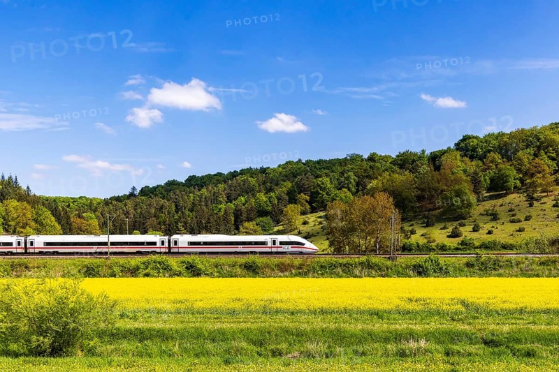 InterCityExpress ICE en route on the Swabian Alb near Lonsee. Landscape on the railway's Filstalline line in spring with rape fields in bloom. Lonsee, Baden-Württemberg, Germany