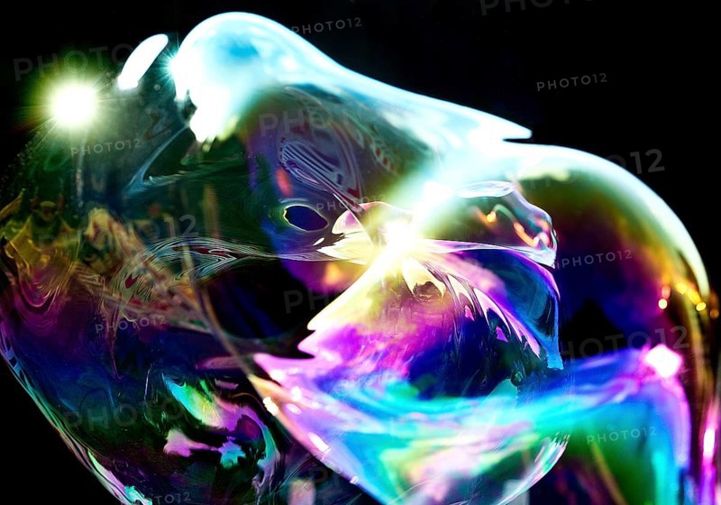 Irregular, iridescent soap bubble in the colours of the rainbow against a black background, Recklinghausen, Germany