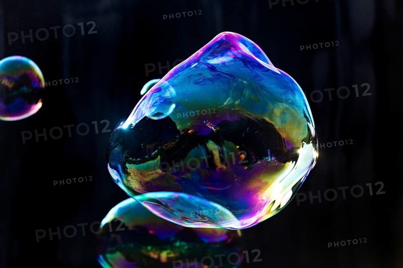 Large, irregular, iridescent soap bubbles in the colours of the rainbow against a black background, Recklinghausen, Germany
