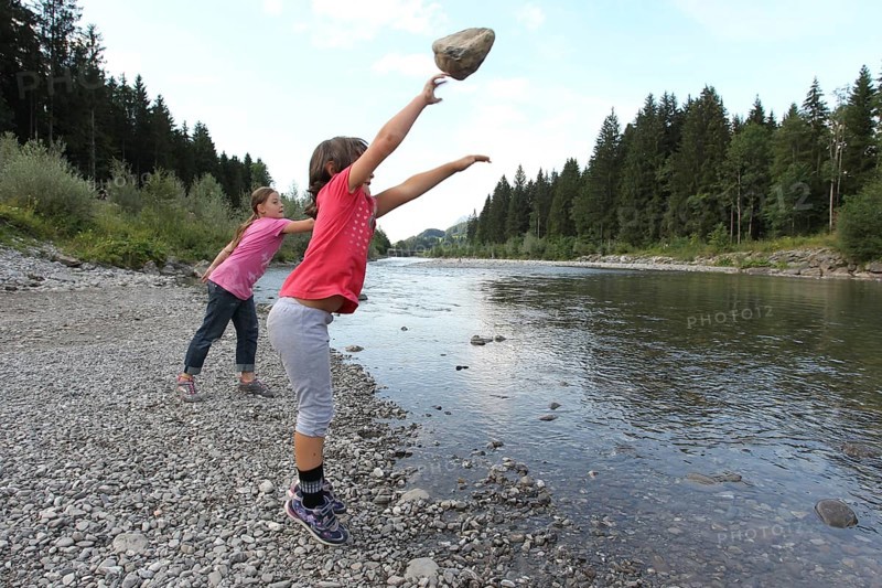 Girls, children throwing stones into a river, activity with children in nature, Allgäu, Bavaria, Germany, Allgäu, Bavaria, Germany
