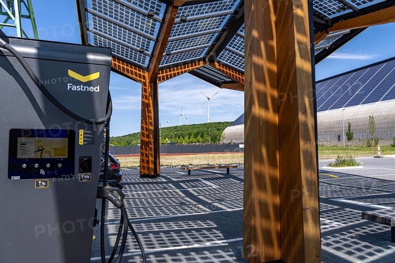 Electric charging station on the site of the former Lohberg colliery in Dinslaken, operated by Fastned, uses electricity from wind power and solar energy, fast-charging columns, with its own solar roof, in the background the 11, 500 square metre solar roof on the colliery's former coal mixing hall, wind farm on the Lohberg slagheap, North Rhine-Westphalia, Germany