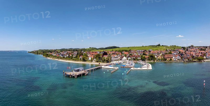 Luftbild, Panorama von der Bodenseegemeinde Hagnau, Winzerdorf und beliebter Ferienort am Bodensee, dahinter Rebhänge, auf denen hauptsächlich die Weinsorten Müller Thurgau und Blauer Burgunder angebaut werden. Am Seeufer der am 23.Mai 2025 eingeweihte, neue Westhafen, Yachthafen mit der Schiffanlegestelle, Bodenseekreis, Baden-Württemberg, Deutschland