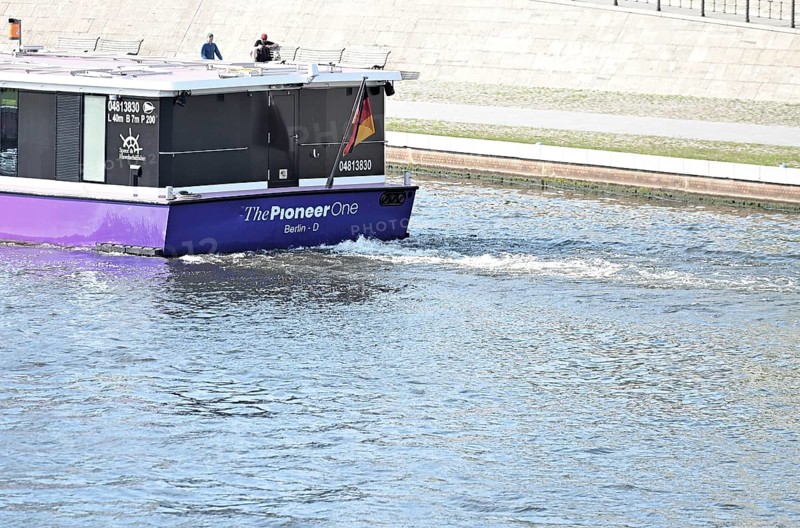 The media ship The Pionieer One sails on the Spree near the Kapelleufer