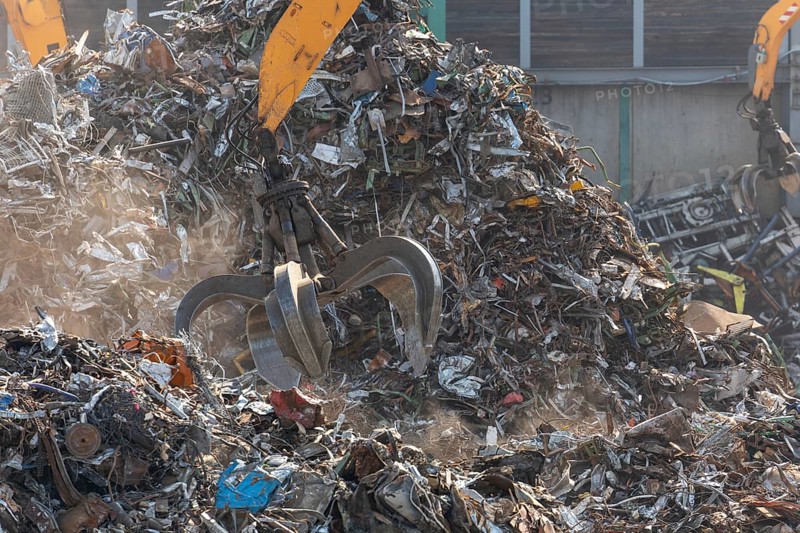 Hydraulic crane lifts scrap metal at the scrap yard