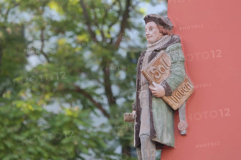 Historical merchant from the 16th century with book and inscription Soll Haben, created in 1933, symbol for order book, economy, orders, balance sheet, orders, economy, financial institution, bank, holding, carrying, under the arn, carrying, house corner, Halle an der Saale, Saxony-Anhalt, Germany