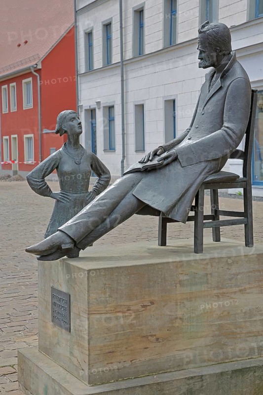 Monument to philosopher Friedrich Nietzsche, bronze sculpture, modern art, standing female figure, girl, sitting on chair, communication, conversation, listening, Holzmarkt, Saale, Naumburg, Saxony-Anhalt, Germany