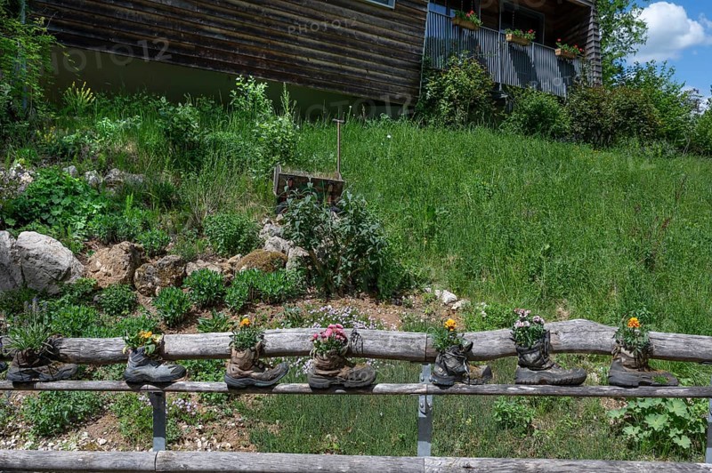 Wooden railing with flowers in worn mountain boots, Bavaria, Germany