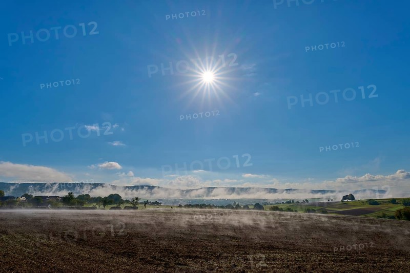 Under a clear sky, the sun shines over a misty, wide landscape, Mönchberg, Miltenberg, Spessart, Bavaria, Germany