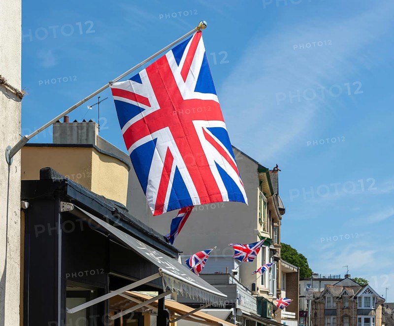Union Jack flags on shops in street of historic buildings, The Strand, Dawlish, south Devon, England, UK