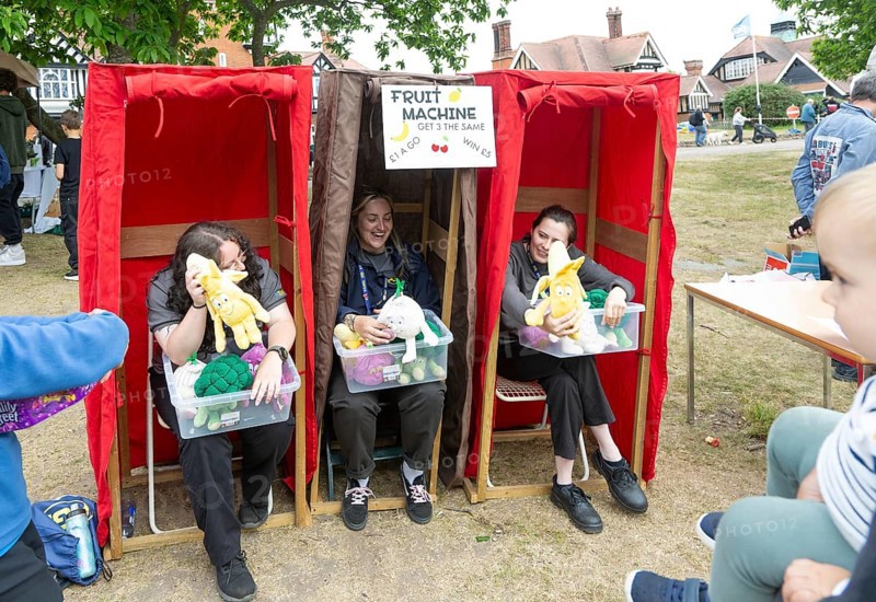 Three women forming human fruit machine game at village summer fete, Bawdsey, Suffolk, England, UK