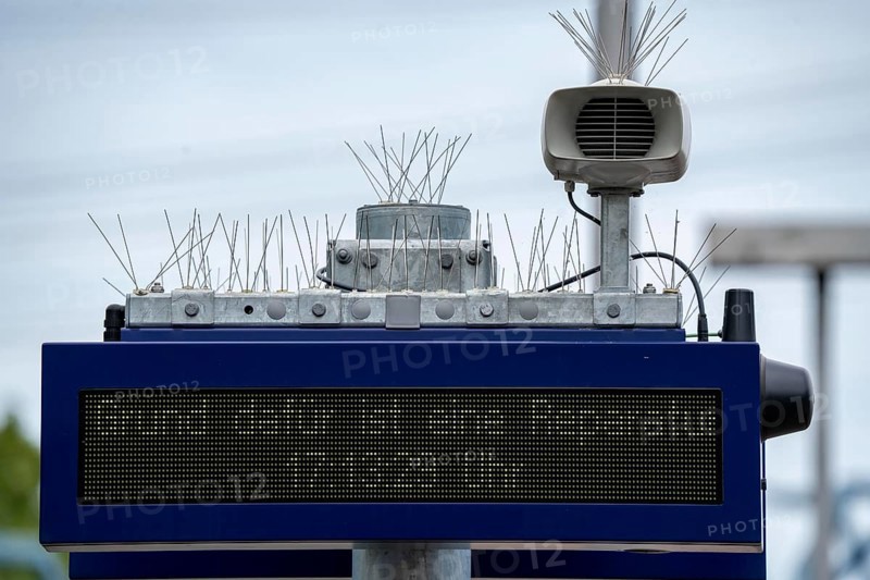 Display board, at a station, train cancellation announcement due to construction work, display shows text with apology for the train cancellation, peppered with thin wires against birds, pigeons, to keep the technical equipment free of bird droppings, bird defence, pigeon defence