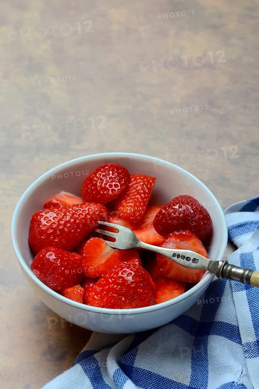 Sliced strawberries in hull with fork, Fragaria