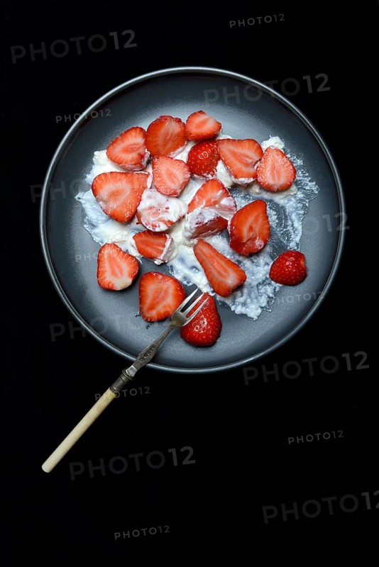 Sliced strawberries and whipped cream on a plate, dessert