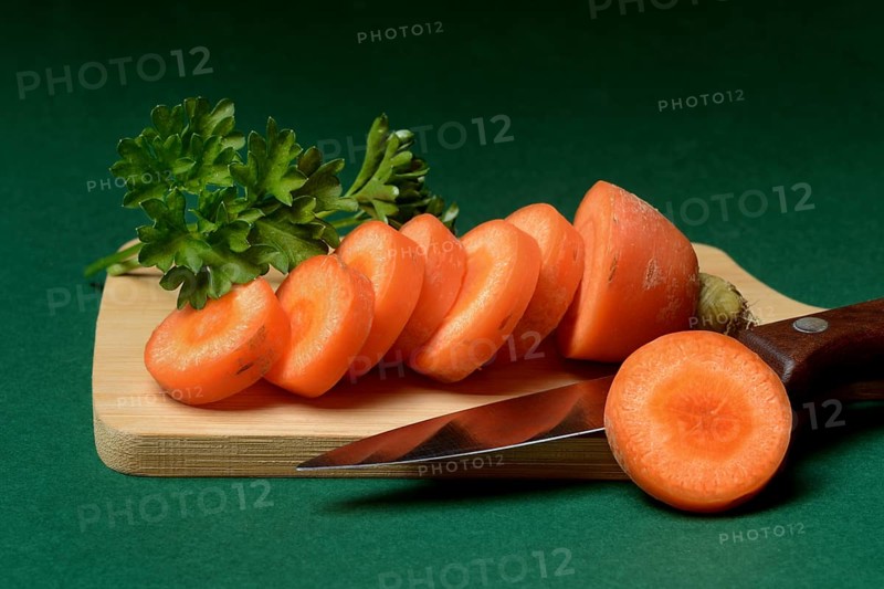 Carrot, carrot slices with kitchen knife on wooden board
