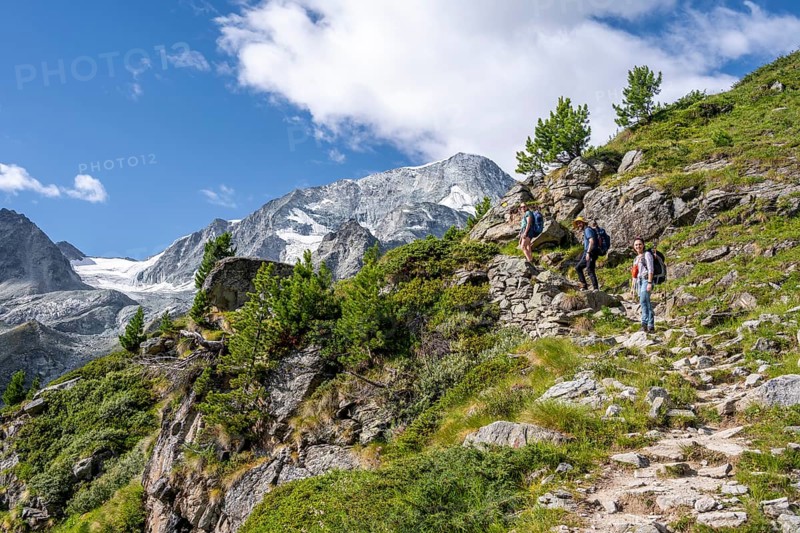 Three mountaineers on a hiking trail, mountain landscape near Arolla, behind mountain peak Mont Collon and glacier Glacier de Tsijore Nouve, Valais, Western Alps, Switzerland