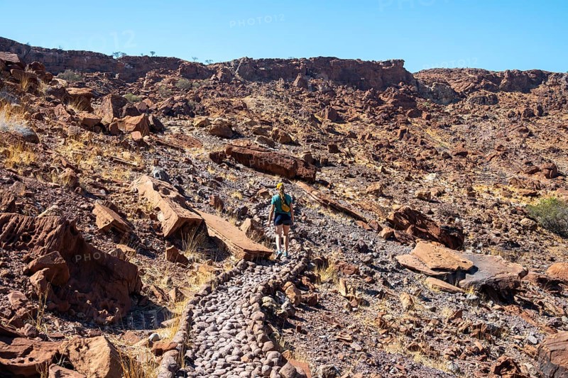Tourist on a hiking trail, Barren landscape in a valley, Twyfelfontein, Kunene, Namibia