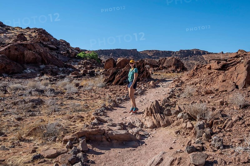 Tourist on a hiking trail in a barren landscape, visiting the rock engravings of Twyfelfontein, Twyfelfontein, Kunene, Namibia