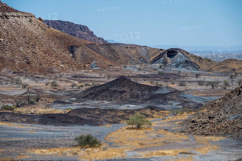 Dry landscape with yellow grass and black volcanic hills, Burnt Mountain, Damaraland, Kunene, Namibia