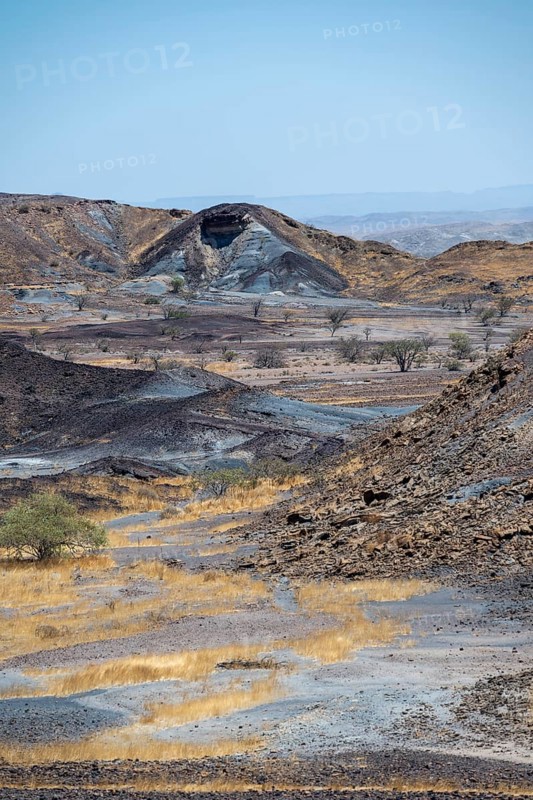 Dry landscape with yellow grass and black volcanic hills, Burnt Mountain, Damaraland, Kunene, Namibia