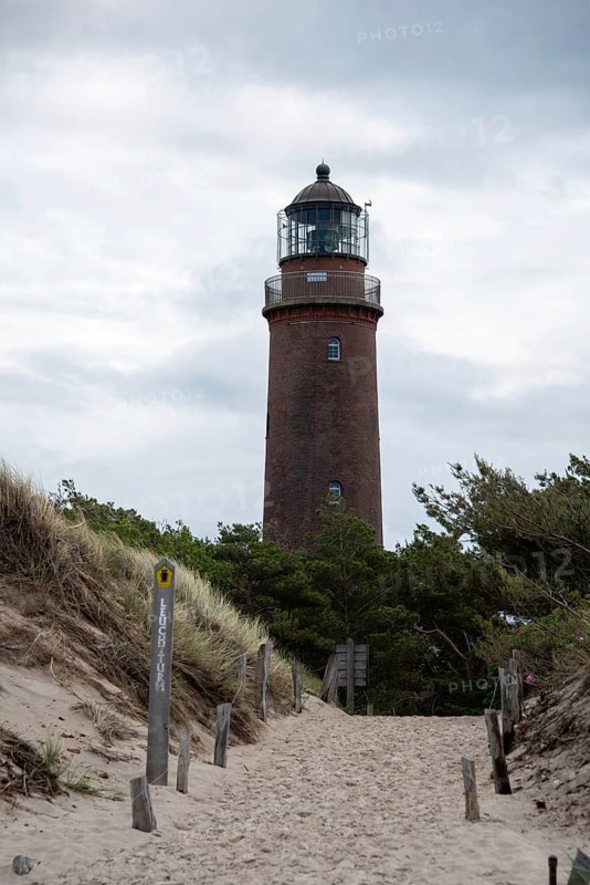 Path through sand dunes leads to the Darßer Ort lighthouse, surrounded by nature and cloudy skies, Prerow, Mecklenburg-Vorpommern, Germany
