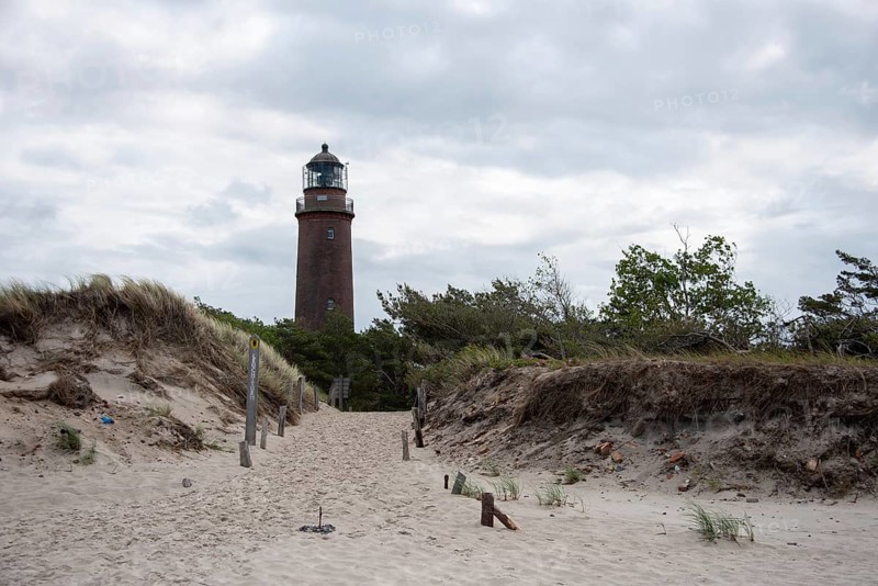 Path through sand dunes leads to the Darßer Ort lighthouse, surrounded by nature and cloudy skies, Prerow, Mecklenburg-Vorpommern, Germany