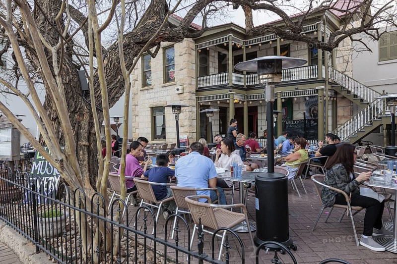 Tourists eating outside on the patio of the Silver Creek Beer Garden in Fredericksburg, Texas, USA