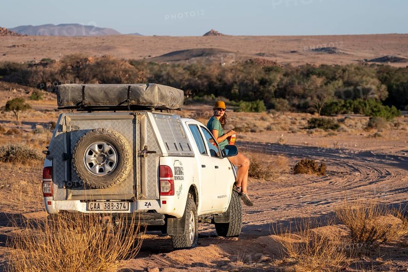 Tourist with off-road car on a sandy track, rock formation, Brandberg, Damaraland, Namibia