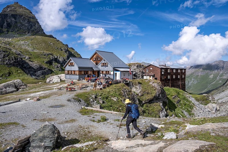 Mountaineer in front of mountain hut Cabane de Prafleuri in mountain landscape, Valais, Western Alps, Switzerland