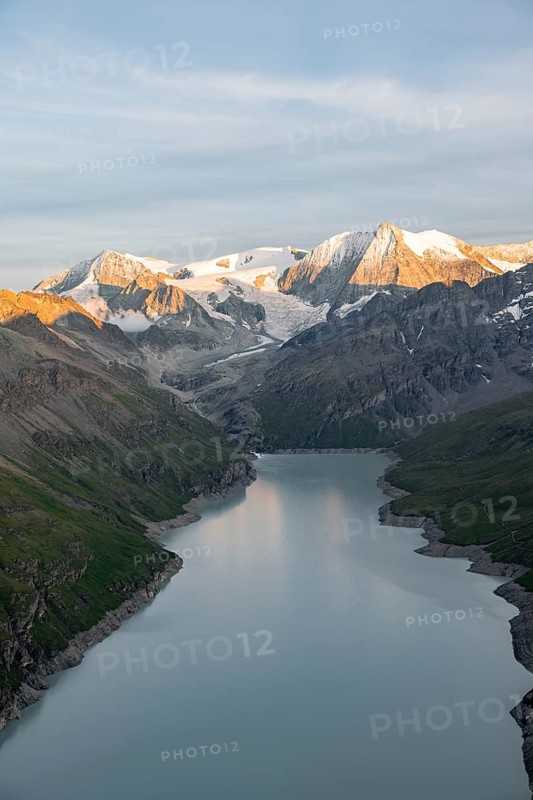 View at the summit of Mont de la Blana, alpenglow at sunset, view of a blue mountain lake, Lac des Dix reservoir, behind mountain peak Mont Blanc de Cheilon with glacier, Hérménence, Valais Alps, Valais, Switzerland