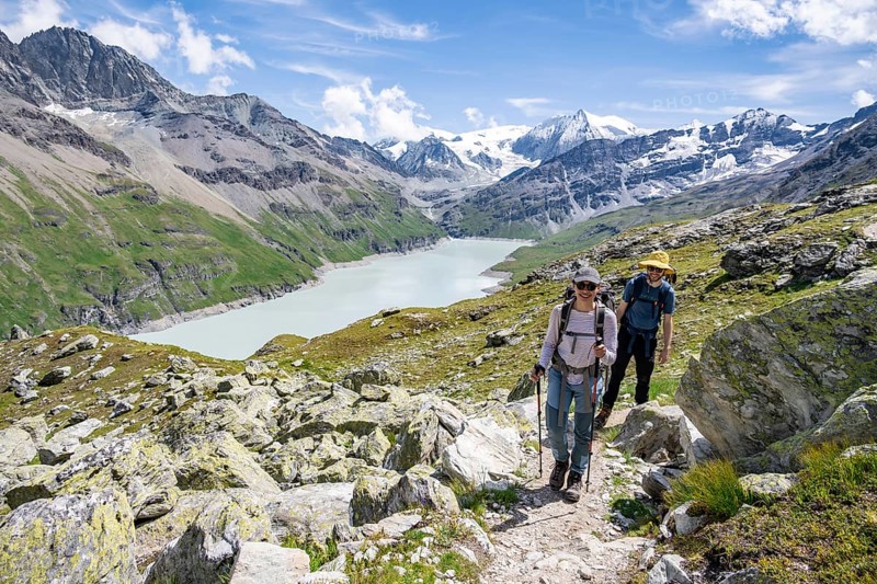 Mountaineer on a hiking trail at a blue mountain lake, reservoir Lac des Dix, behind mountain peak Mont Blanc de Cheilon, Hérménence, Valais Alps, Valais, Switzerland