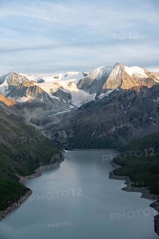 View at the summit of Mont de la Blana, in evening light, view of a blue mountain lake, reservoir Lac des Dix, behind mountain peak Mont Blanc de Cheilon with glacier, Hérménence, Valais Alps, Valais, Switzerland