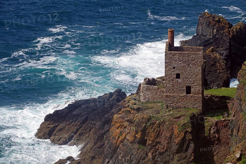 An old stone house perched on cliffs above a stormy sea with crashing waves, engine room, mining, Botallack, Cornwall, England, United Kingdom