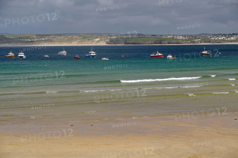 Several boats floating on a calm sea in front of a misty coastline, St Ives, Cornwall, England, United Kingdom