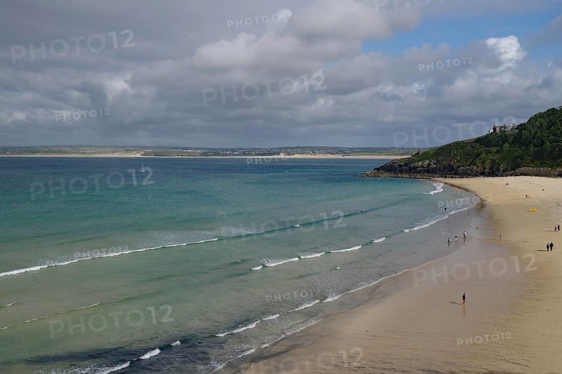 Spacious beach with gentle waves and few people under a cloudy sky, St Ives, Cornwall, England, United Kingdom