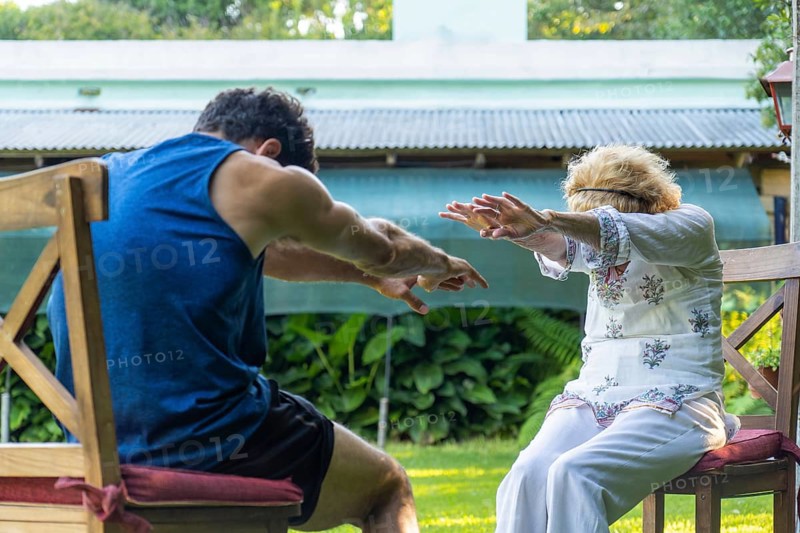 Physiotherapist assisting a senior woman with rehabilitation exercises in a vibrant home garden, enhancing health and mobility while promoting a healthy lifestyle outdoors