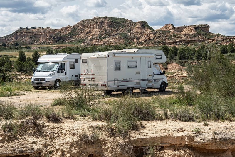 Camper van, colorful sandstone rock formations, desert, gravel road Ruta Jubierre, Desierto de los Monegros, Spain
