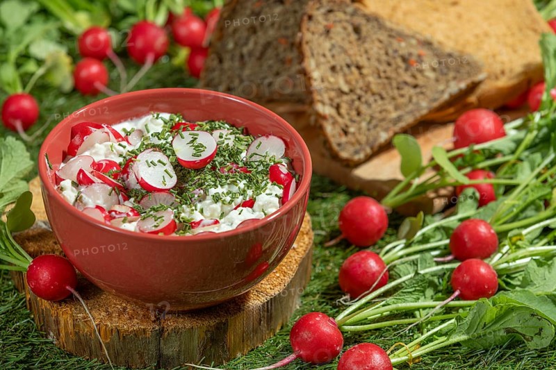 Cream cheese with radishes and herbs, next to slices of bread