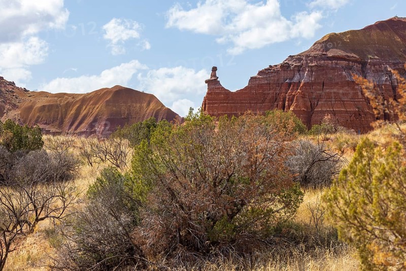 The Lighthouse rock hoodoo behind a field of grass and shrubs at Palo Duro Canyon State Park near Amarillo, Texas