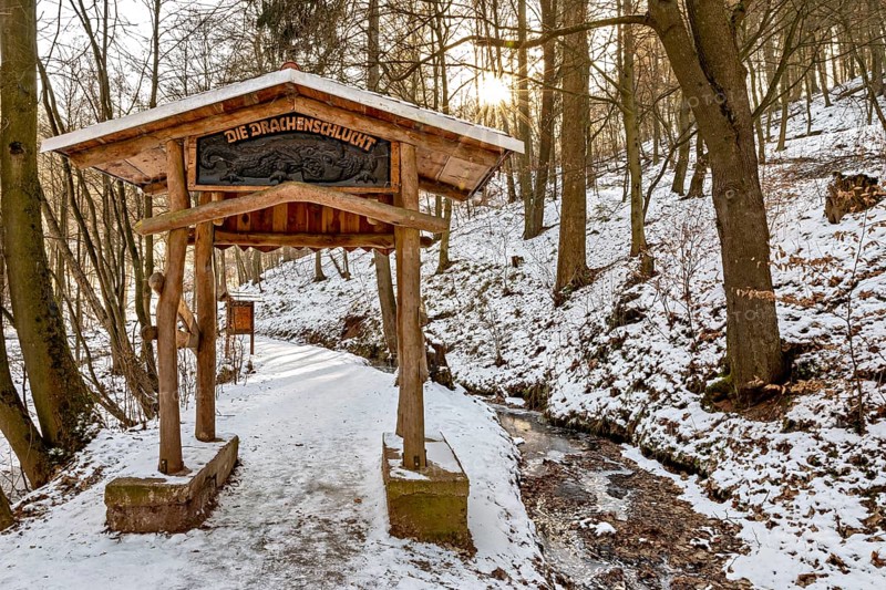 Snow-covered forest gate with stream under sunlight, The Dragon Gorge near Eisenach in Thuringia