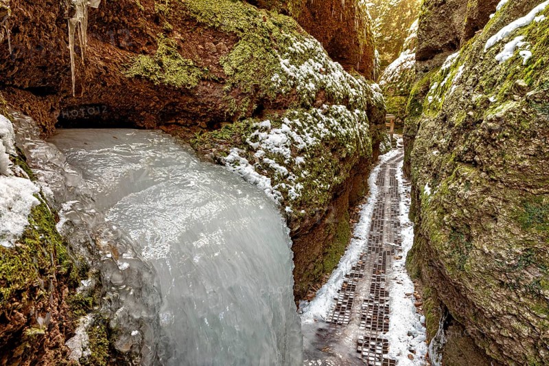 Frozen waterfall in a narrow gorge, lined with mossy rocks and snow, The Dragon Gorge near Eisenach in Thuringia