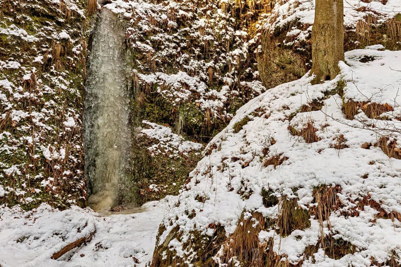 Frozen waterfall in a rocky environment with snow-covered ground and trees, The Dragon Gorge near Eisenach in Thuringia
