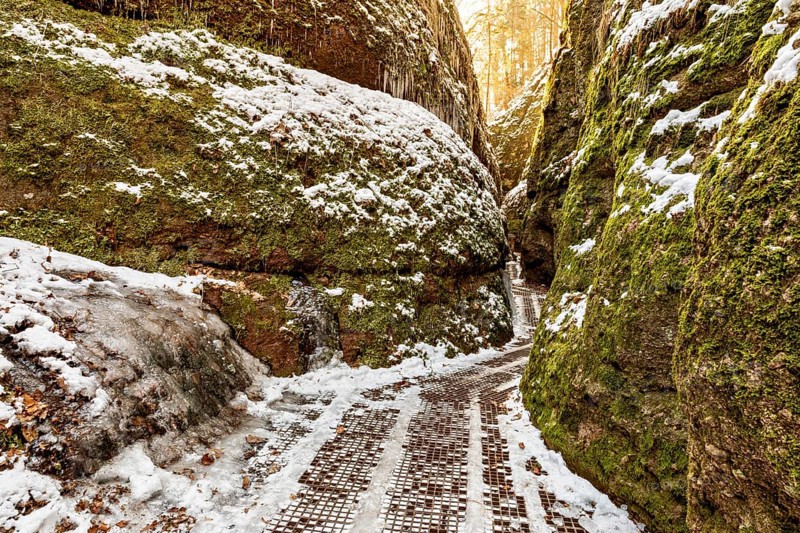 Snow-covered path between moss-covered rock faces in a quiet winter gorge, the Dragon Gorge near Eisenach in Thuringia