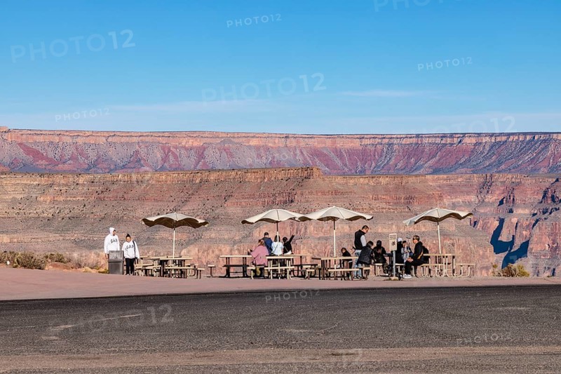 Tourists waiting for bus transportation at covered picnic tables at Guano Point in Grand Canyon West near Peach Springs, Arizona