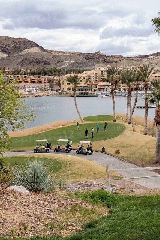 Senior golfers teeing off while playing on a golf course along the shoreline of Las Vegas Wash at Lake Las Vegas in Henderson, Nevada, USA