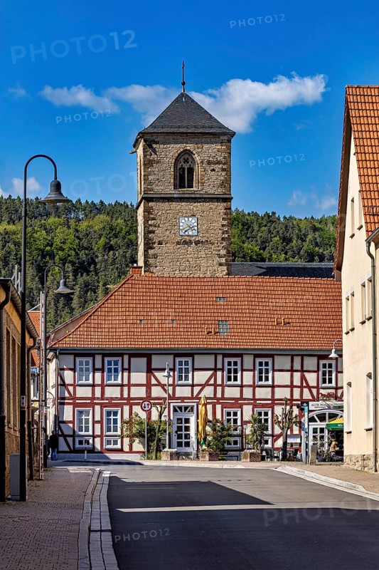 A half-timbered house with a church tower in the village, shining under a blue sky, The church tower of the Protestant church of Creuzburg in Thuringia