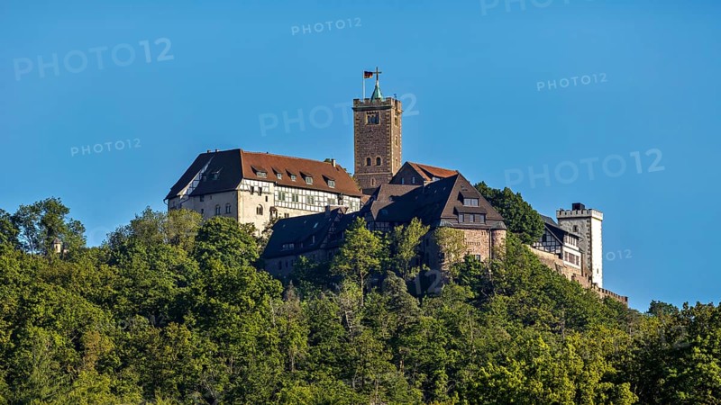 Castle with striking tower rises above green forests, Wartburg Castle near Eisenach in Thuringia