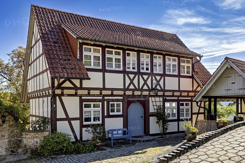 A traditional half-timbered house with red roof tiles and bench in a sunny rural courtyard, Historic half-timbered houses in the town of Treffurt in Thuringia